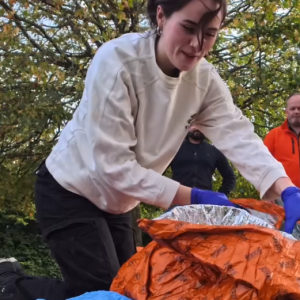 Lady kneeling on the ground performing first aid training during a simulation